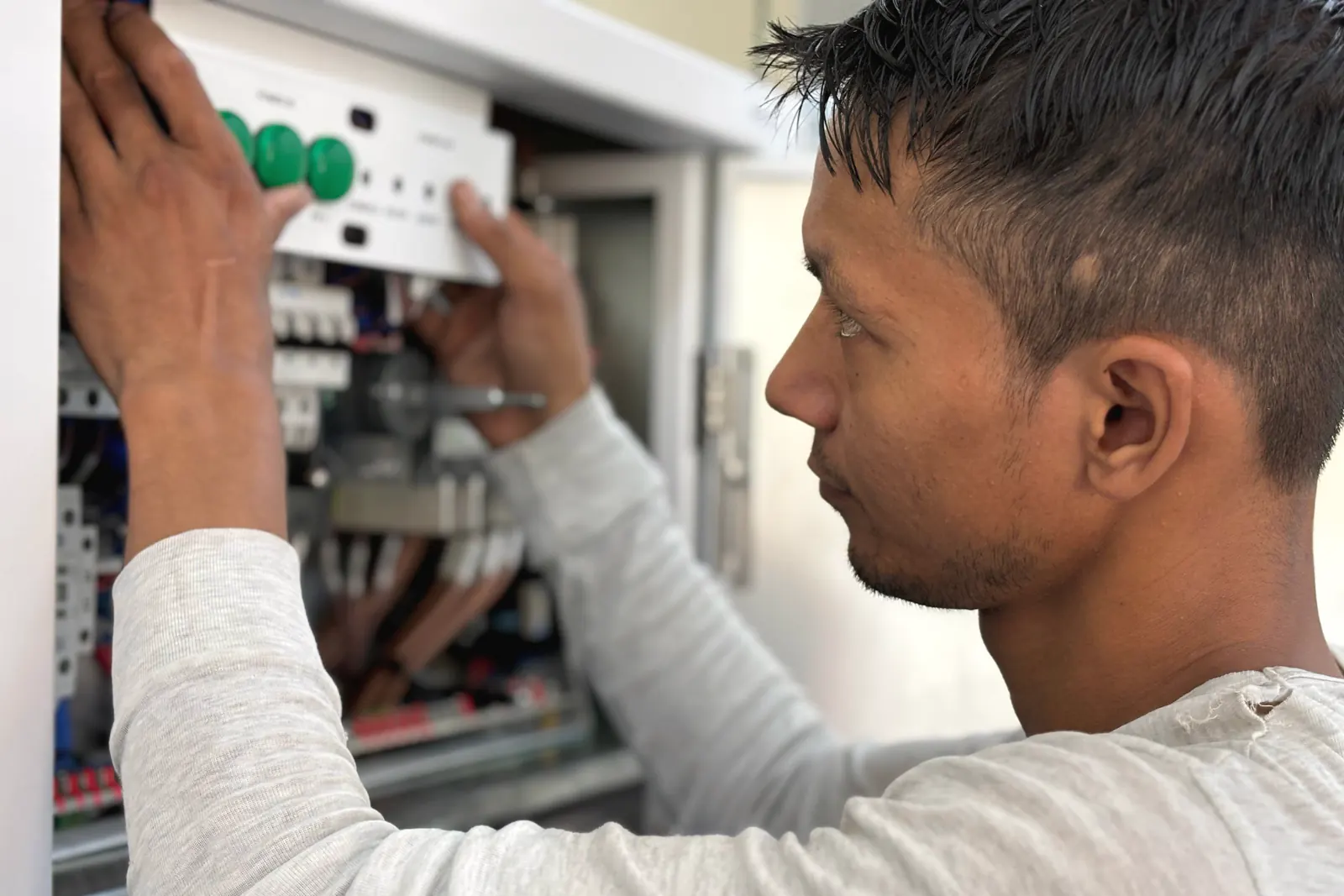 Electrician working on an open electrical panel.